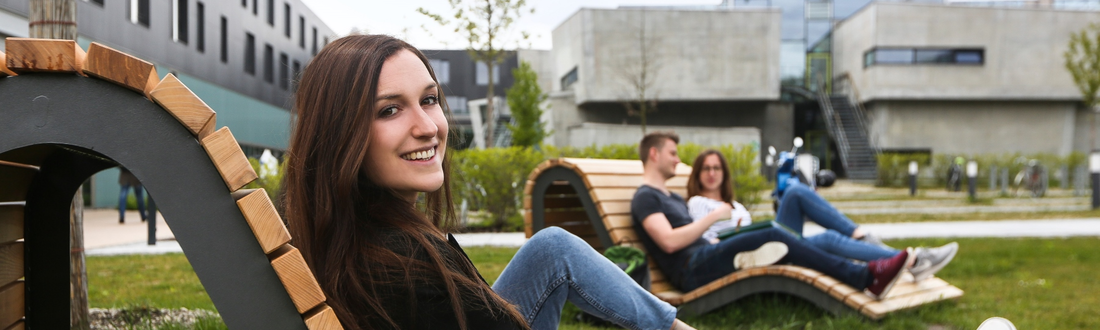 Studierende auf Holzliege auf Campuswiese