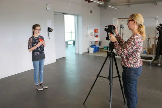 Eine Frau fotografiert ein Mädchen mit einer Wärmebildkamera auf einem Stativ