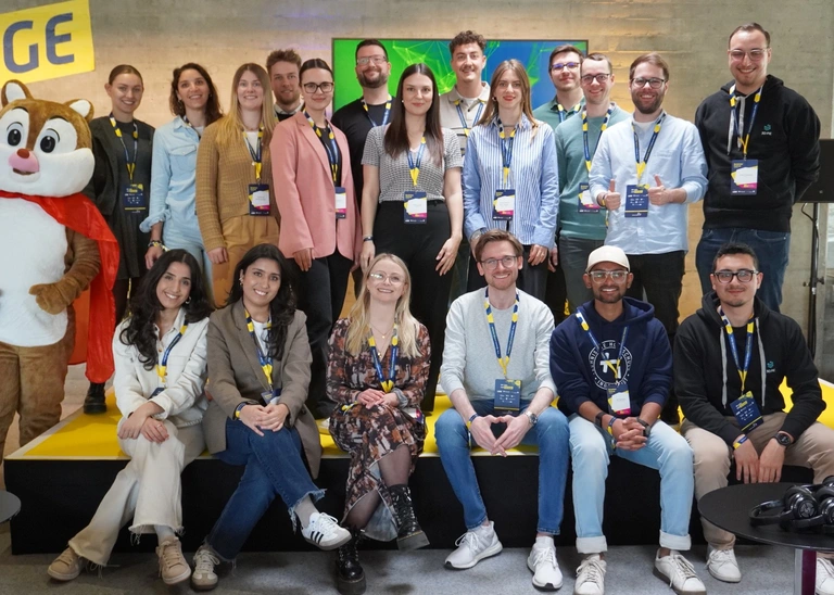 A group photo with 19 people and a mascot.